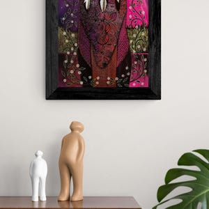 May include: A framed artwork featuring a vibrant, colorful depiction of three figures with feathered headdresses. The artwork has a dark wooden frame and is set against a backdrop of pink, purple, and white hues. Decorative floral elements are present.