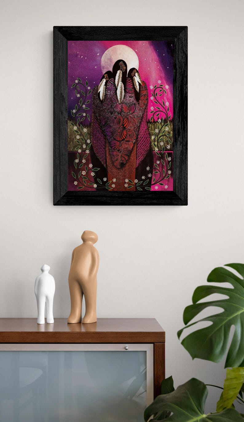 May include: A framed artwork featuring a vibrant, colorful depiction of three figures with feathered headdresses. The artwork has a dark wooden frame and is set against a backdrop of pink, purple, and white hues. Decorative floral elements are present.