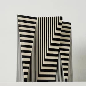 以下が含まれることがあります： 印象的な錯視デザインの白黒幾何学彫刻。アートワークは、垂直および角度のストライプを特徴とし、3次元効果を生み出しています。彫刻はモダンアート作品です。