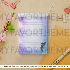 May include: A lined notepad with a watercolor design in shades of purple and blue, featuring a fairy illustration. The notepad is surrounded by stationery items, including paperclips, a pen, and an envelope. The text "MYFAVORTHEME" is visible.