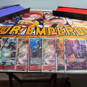 May include: Five trading cards featuring characters from the anime One Piece. The cards are arranged in a row from left to right. The characters are Edward Newgate, Koala, Karoo, Koala, and Gecko Moria. The cards are all in a holographic style with a black background.
