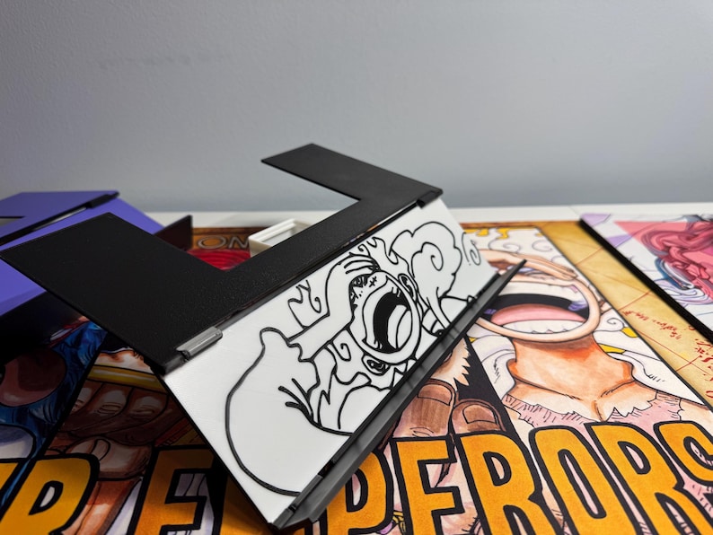 May include: A black and white drawing of a character with a large mouth and a cloud behind them. The drawing is on a white background and is inside a black frame. The frame is sitting on top of a colorful comic book page with the word "emperors" printed in yellow.