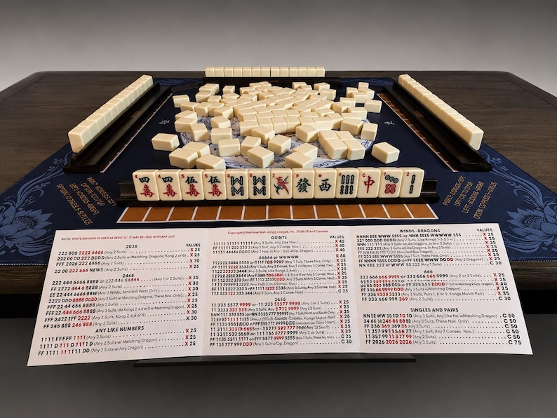 Puede incluir: Un juego de Mahjong completo con fichas y soportes de color marfil, dispuestos sobre una superficie de juego azul con caracteres chinos. Se ve una gu&iacute;a impresa con las reglas del juego. El juego est&aacute; sobre una mesa de madera oscura.