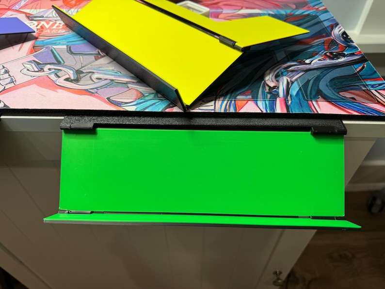 May include: A black frame with a green background. The frame is attached to a white surface.