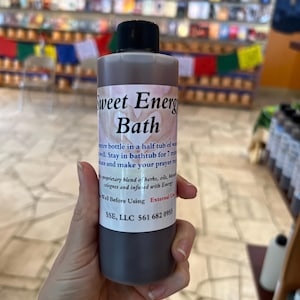 May include: A brown glass bottle with a black cap labeled "Sweet Energy Bath". The bottle contains a dark liquid and has instructions for use, including a phone number for SSE, LLC.