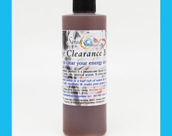 May include: A brown glass bottle with a black cap labeled "Sarah Spiritual" and "Energy Clearance Bath" with the text "to clear your energy and..."  The bottle is filled with a dark brown liquid.