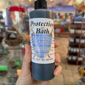 May include: A dark blue glass bottle with a black label that reads "Protection Bath". The label also includes instructions for use and a phone number for SSE, LLC.