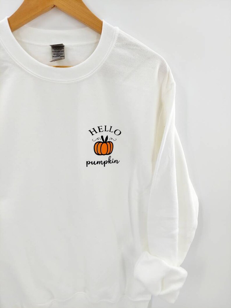 May include: White sweatshirt with a black and orange pumpkin graphic and the text "HELLO pumpkin" on the front.