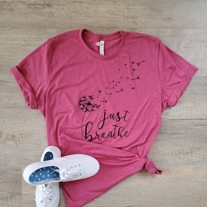 May include: A pink t-shirt with a black dandelion graphic and the text "just breathe".