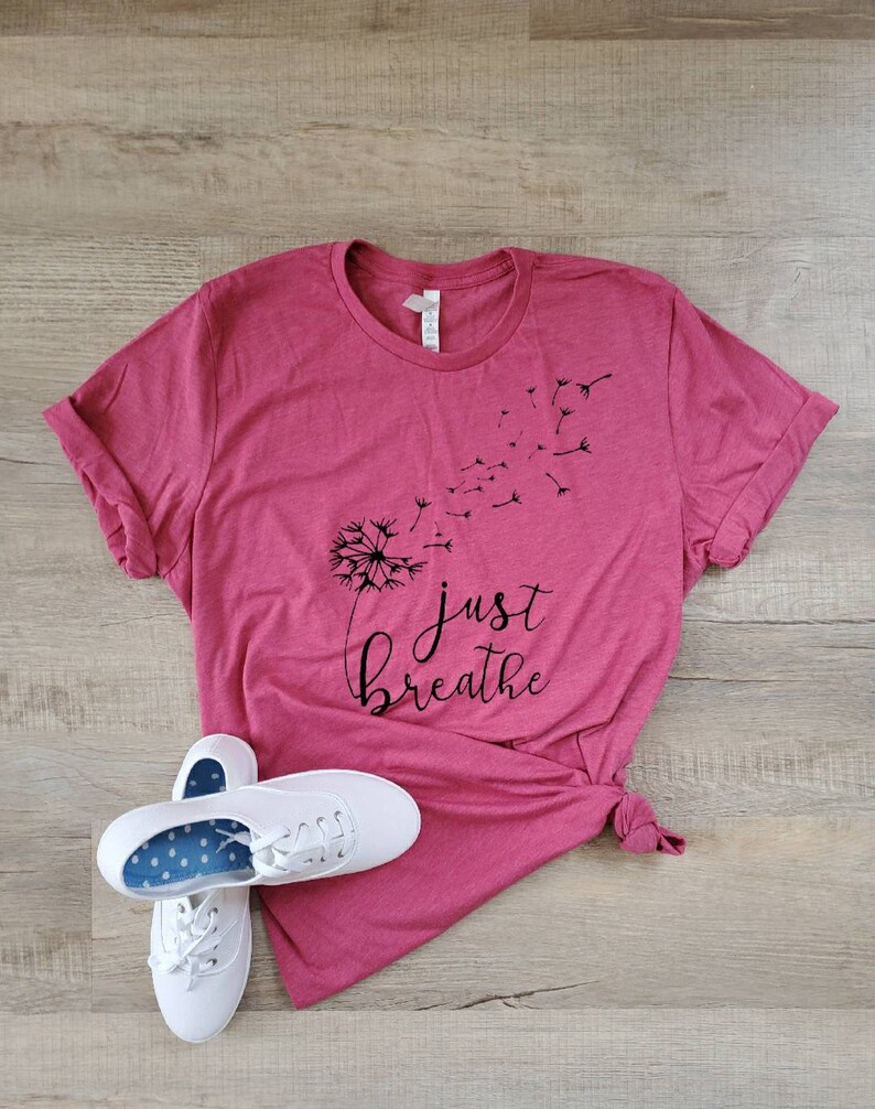 May include: A pink t-shirt with a black dandelion graphic and the text "just breathe".