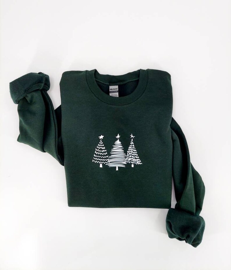 May include: A dark green sweatshirt with a white design of three stylized Christmas trees on the front.