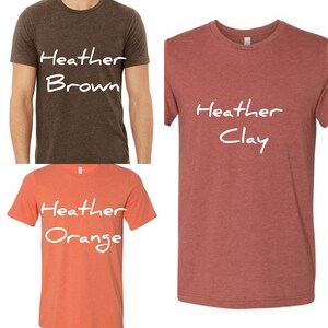 May include: Three t-shirts in different colors: heather brown, heather clay, and heather orange. Each shirt has the word "Heather" written on it, followed by the color of the shirt.