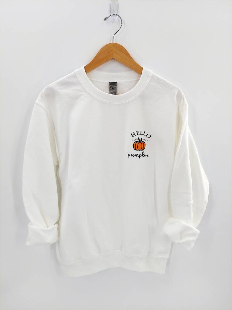 May include: White sweatshirt with a small orange pumpkin graphic and the text "HELLO pumpkin" on the front.