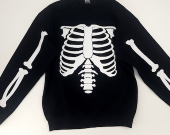 May include: Black sweatshirt with a white skeleton graphic printed on the front. The skeleton graphic includes the rib cage, spine, and arm bones.