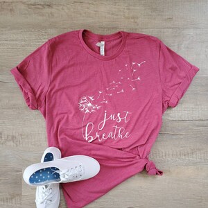 May include: A maroon t-shirt with a white dandelion graphic and the text "just breathe".
