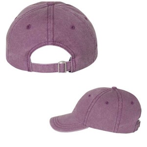 Puede incluir: Una gorra de b&eacute;isbol de color morado con un aspecto ligeramente desgastado. La gorra tiene una visera curvada y una correa ajustable en la parte posterior.