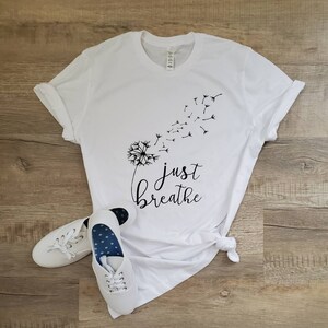 May include: White t-shirt with a black dandelion graphic and the text "just breathe".