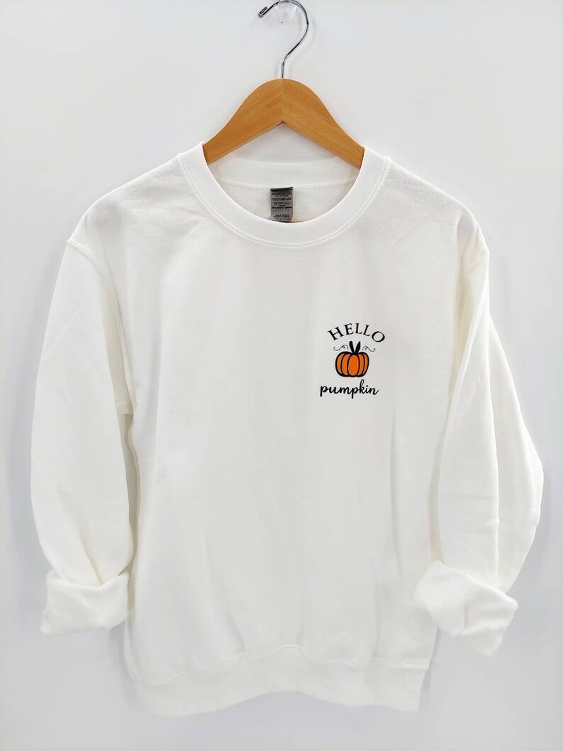 May include: White sweatshirt with a pumpkin graphic and the text "Hello pumpkin" in black.