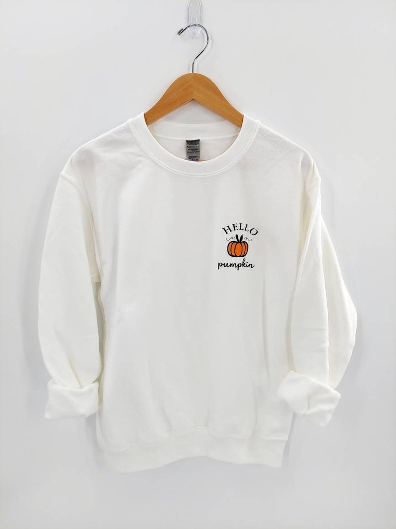 May include: White sweatshirt with a small orange pumpkin graphic and the text "HELLO pumpkin" on the front.