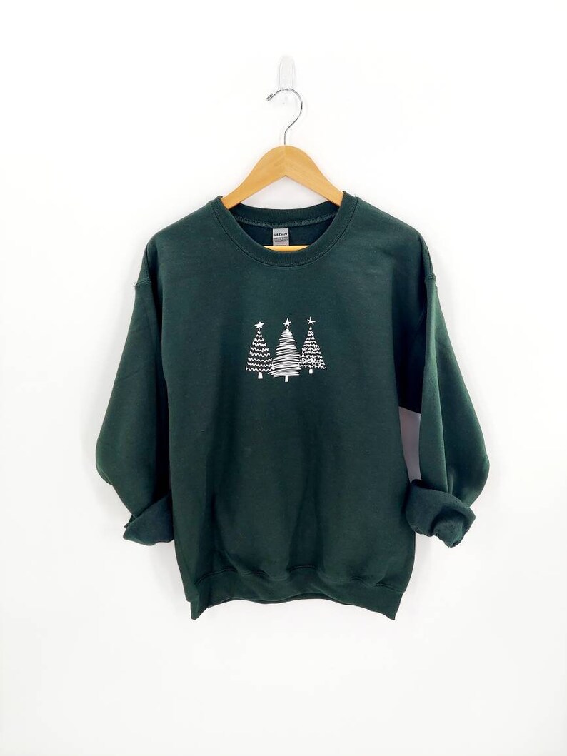 May include: A dark green sweatshirt with a white design of three stylized Christmas trees on the front.