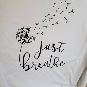 May include: White t-shirt with a black dandelion design and the text "just breathe" printed on it.