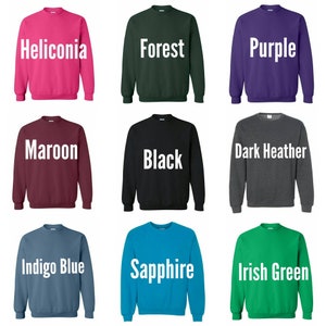 May include: Nine different color crew neck sweatshirts. The colors are Heliconia, Forest, Purple, Maroon, Black, Dark Heather, Indigo Blue, Sapphire, and Irish Green.
