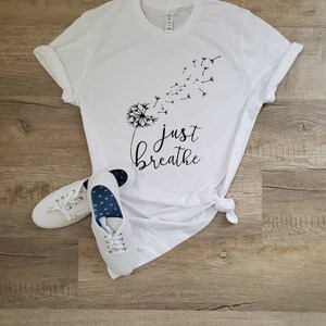 May include: White t-shirt with a black dandelion graphic and the text "just breathe".
