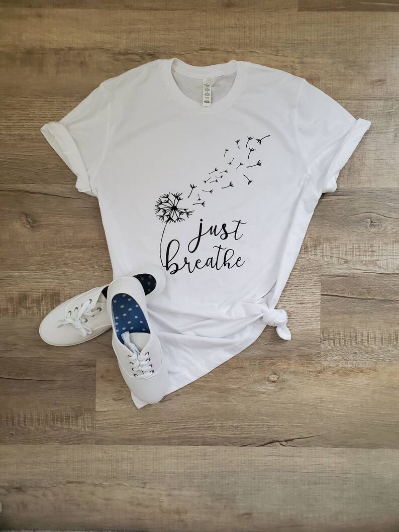 May include: White t-shirt with a black dandelion graphic and the text "just breathe".