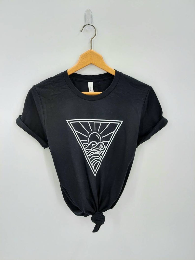 May include: Black t-shirt with a white graphic of a sun and waves inside a triangle.