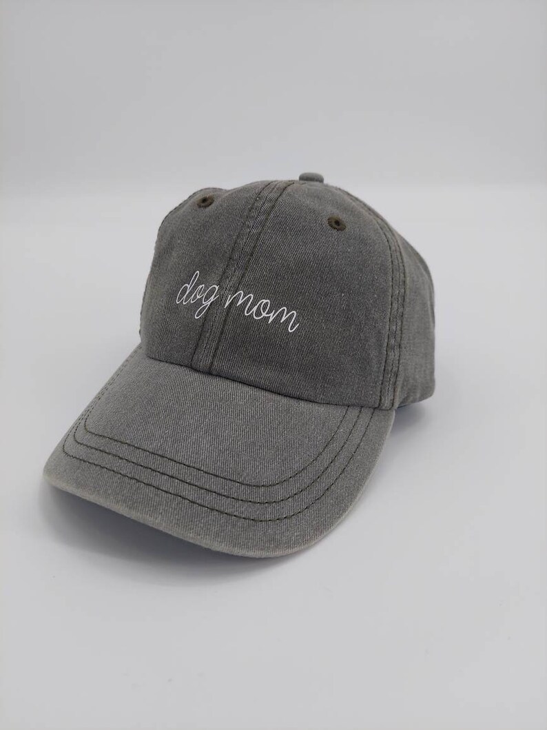 Puede incluir: Una gorra de b&eacute;isbol gris con el texto "dog mom" bordado en blanco en la parte delantera.