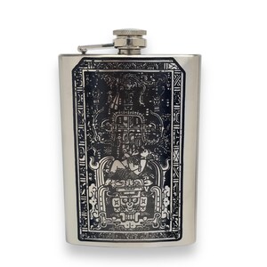 May include: A silver flask featuring a black and white design of an ancient Mayan figure. The design is intricate and detailed, making this flask a stylish way to carry your favourite drink.