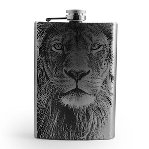 May include: A silver flask with a black and white lion face etched on the front.