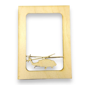 May include: A wooden picture frame with a cutout of a helicopter in the bottom centre of the frame.