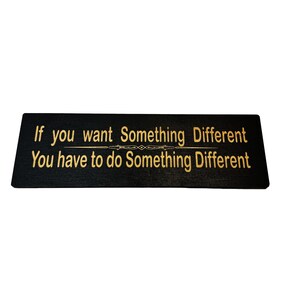 May include: Black wooden sign with gold lettering that reads "If you want something different you have to do something different."