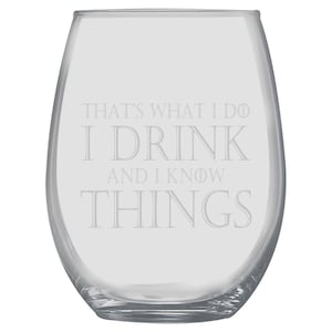 以下が含まれることがあります： 「THAT'S WHAT I DO I DRINK AND I KNOW THINGS」の文字が刻まれた、透明なステムレスワイングラス。丸みを帯びたボウルと平らな底が特徴です。テキストはセリフ体です。