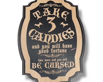 Puede incluir: Letrero de Halloween de madera con un centro negro y un borde marrón claro. El letrero dice "TAKE 3 CANDIES and you will have good fortune, take more and you will BE CURSED" en una fuente gótica. Murciélagos aparecen encima de la palabra "CANDIES".