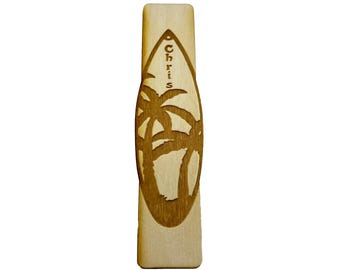 May include: A wooden surfboard keychain with a palm tree design and the name "Chris" engraved on it.