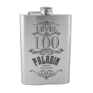 Puede incluir: Una petaca de acero inoxidable plateada con un diseño grabado en negro que dice "Nivel 100 Paladin Venganza Divina".
