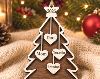 May include: A wooden Christmas tree ornament featuring a dark brown tree shape with a light wood border. It includes a red and black buffalo plaid bow at the top, a star labeled 2026, and four hanging heart cutouts engraved with Dad, Mom, Yoselin, and Brandon.