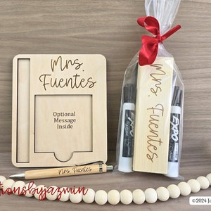 May include: A teacher gift set with a wooden picture frame, a pen, and a gift bag containing dry-erase markers and a wooden sign, all engraved with "Mrs. Fuentes". The frame has space for an optional message.