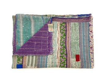 Könnte beinhalten: Eine Patchwork-Decke mit verschiedenen Farben und Mustern, darunter Lila, Grün, Blau und Weiß. Die Decke besteht aus verschiedenen Stoffen, die zusammengenäht wurden und ein einzigartiges und strukturiertes Design ergeben.