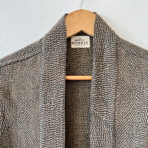 May include: A brown and black patterned kimono with a label that reads "The Brighton Bombay Company".
