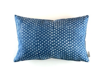 May include: A blue and white patterned pillow with a white polka dot design. The pillow is made of a soft, textured fabric.