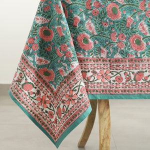 Puede incluir: Un mantel de mesa de color turquesa con un patrón floral en tonos rosa y verde. El mantel tiene un borde con un diseño floral repetitivo.