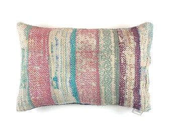 May include: A rectangular pillow with a striped pattern in shades of pink, blue, and white. The pillow is made of a woven fabric and has a slightly distressed look.