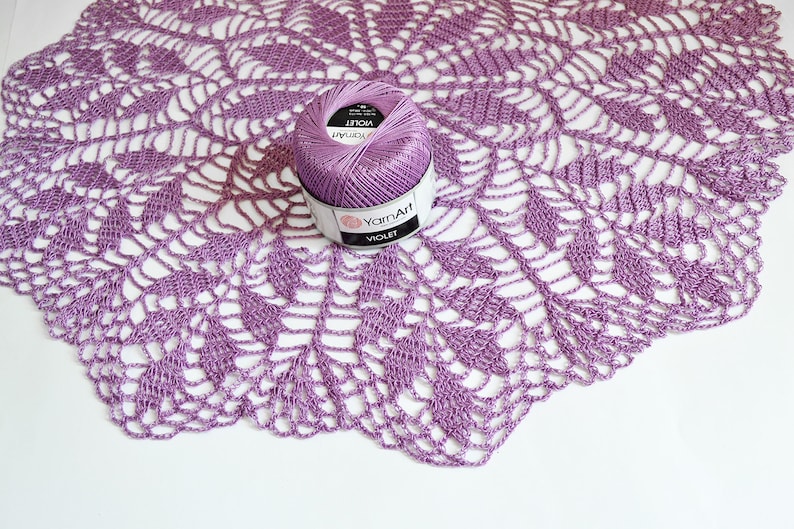 Puede incluir: Un encaje de ganchillo morado con una madeja de hilo de arte de color morado etiquetada como "Violet" en el centro.