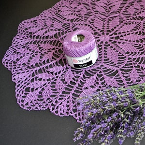Puede incluir: Un encaje de ganchillo morado con un ovillo de hilo morado y un ramo de flores de lavanda.