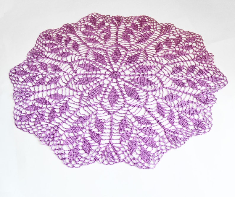 Puede incluir: Un gran encaje de ganchillo redondo de color morado con un dise&ntilde;o delicado e intrincado.