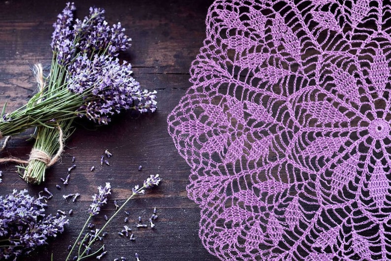 Puede incluir: Un encaje de ganchillo morado con un delicado patr&oacute;n floral, sobre un fondo de madera r&uacute;stica con ramitas de lavanda.