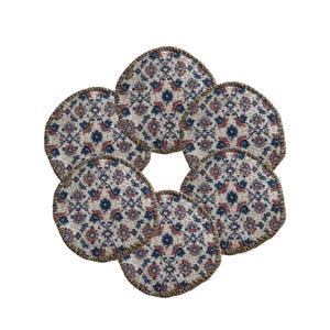 May include: Six round coasters with a floral pattern in shades of blue, red, and beige. Each coaster has a brown stitched edge. The coasters are arranged in a circular shape, resembling a flower.